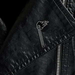 Macro shot of a black enamel flame matchstick brooch pinned on a black leather jacket