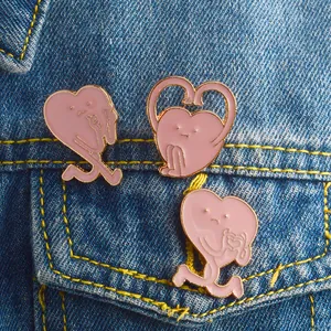 Lot de trois broches en émail rose en forme de cœur sur une poche en jean bleu