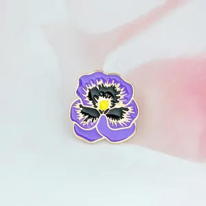 Détail d'une broche pensée en émail violet et jaune avec des bordures en métal doré
