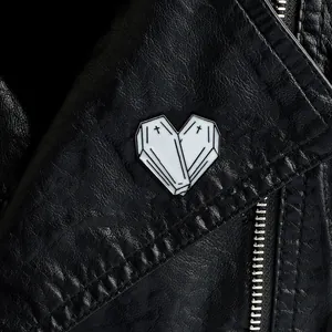 Gothic white heart coffin enamel pin with black cross on a black leather jacket background