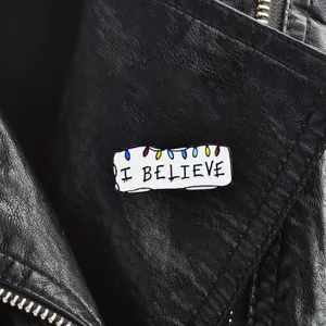 Broche en émail avec texte I BELIEVE et lumières colorées sur une veste en cuir noir