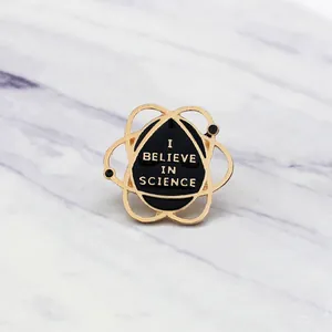 Macro detail of I BELIEVE IN SCIENCE enamel pin with gold atomic orbital design