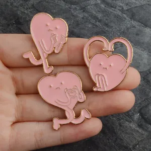 Détail de trois jolies broches cœur en émail rose avec bordure dorée à la main