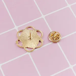 Detail of golden floral brooch base and butterfly clutch pin back on pink pattern