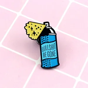 Blue enamel spray bottle brooch with Bullshit Be Gone text on pink tile background