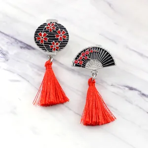 Broche japonaise avec éventail, lanterne et pompons rouges sur fond de marbre