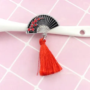 Détail d'une broche éventail en émail avec fleurs de prunier et pompon rouge