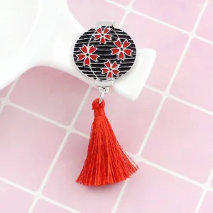Détail d'une broche en émail japonais avec fleurs de cerisier rouges et longs glands en soie