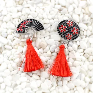 Vue détaillée des boucles d'oreilles rétro avec motif éventail et pompons en soie rouge