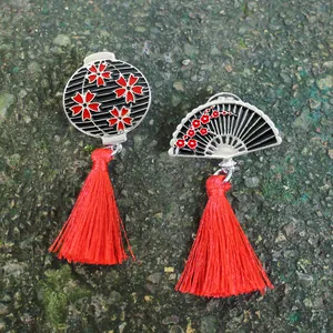 Détail d'une broche orientale en émail en forme d'éventail avec pompons rouges