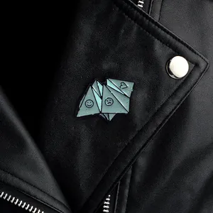 Detail of blue origami face enamel pin with glitter finish on black leather jacket