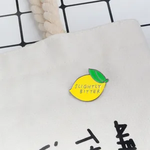 Enamel lemon brooch with Slightly Bitter slogan pinned on a canvas backpack strap