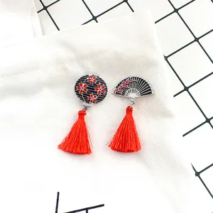 Détail du broche éventail et fleur style japonais avec pompons rouges sur toile blanche