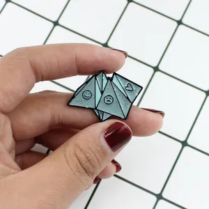 Detailed view of light blue enamel origami brooch with happy face and heart symbols