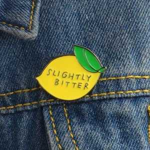 Slightly Bitter enamel lemon pin featuring a bright yellow design on denim jacket
