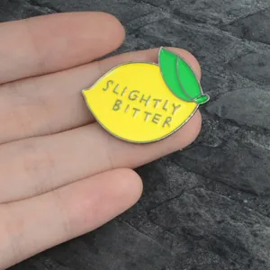 Macro shot of Slightly Bitter lemon enamel pin with yellow metal alloy and green leaf detail
