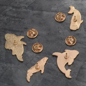 Détail de broches marines dorées avec fermoirs papillon et texture métallique brillante