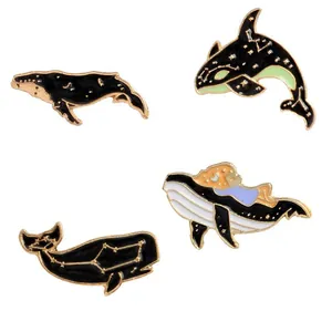 Vue détaillée de quatre broches en émail océan avec baleines et motifs constellations