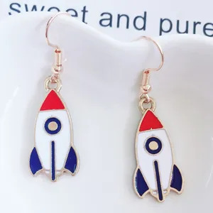 Detalle de pendientes de cohete en rojo, blanco y azul sobre una bandeja de cerámica