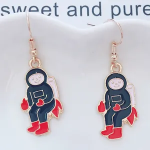 Primer plano de bonitos pendientes de astronauta esmaltados con ganchos dorados