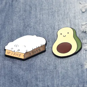 Enamel cat in box and avocado brooch set with 'IF I FITS I SITS' text on denim
