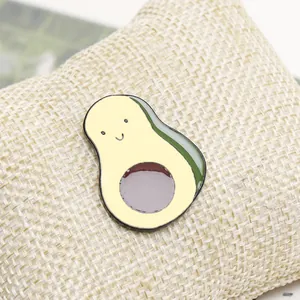 Macro view of a cute cartoon avocado enamel pin with a smiling face on woven fabric