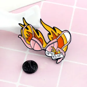 Macro detail of enamel bikini brooch featuring orange flames and IT'S LIT slogan banner