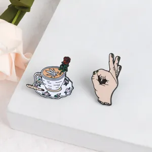 Detail of enamel pins featuring a coffee cup with a rose and an OK hand gesture set