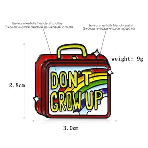 Cartoon suitcase enamel pin with rainbow and Don't Grow Up slogan in red finish