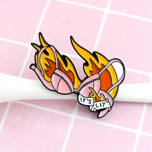 Pink bikini bra enamel pin with flaming design and IT'S LIT text on white banner