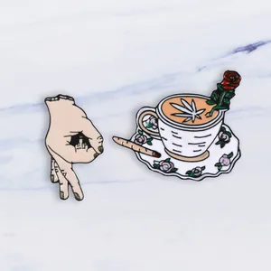 Detail of enamel pins featuring a coffee cup with rose and a punk gesture motif