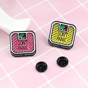 Don't Panic enamel pins featuring pink and yellow scale designs with rubber backings