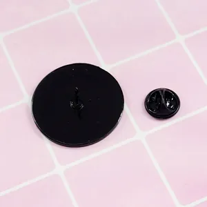 Vue arrière du pin's rond en émail noir avec fermoir métallique sur fond à carreaux roses