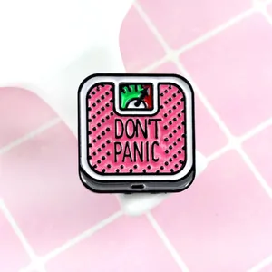 Macro shot of Don't Panic scale enamel brooch with pink dots and vintage metal finish