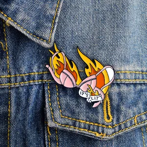 Macro shot of an IT'S LIT flame bikini enamel pin attached to a blue denim jacket pocket