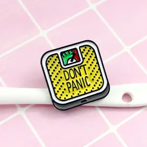 Macro shot of Don't Panic enamel brooch shaped like a retro yellow weighing scale