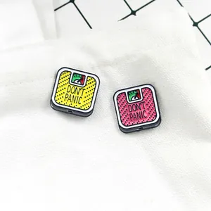 Detail showing yellow and pink enamel scale brooches with Don't Panic text on canvas