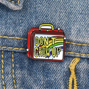 Detail of red cartoon lunchbox enamel pin with rainbow and Don't Grow Up slogan