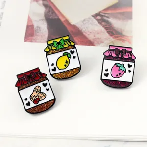 Detailed close-up of fruit jam jar enamel pins with glitter finish and cute heart details