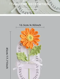 Detail view of handmade crochet orange daisy flower on white stand for tabletop decor