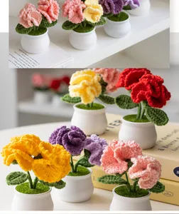 Macro detail of handmade crochet carnation flowers in colorful pots on a bright table