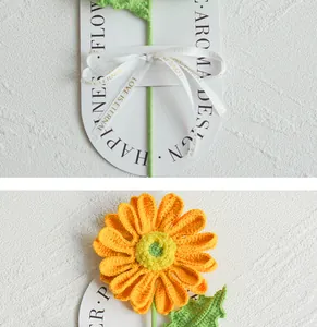Macro detail of hand-knitted sunflower with green stem on white card and decorative ribbon