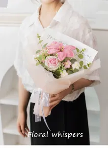 Detalle de ramo de flores tejidas a mano con lirios y rosas rosas en papel de regalo