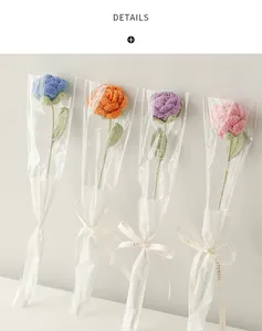 Detail of four handmade knitted roses in various colors with Love Is Eternal gift packaging