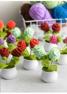 Close-up of handmade crochet flower pots featuring knitted blossoms and green leaves