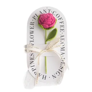 Handmade crochet pink rose with green leaves on decorative card with golden ribbon