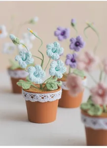 Close-up of hand-knitted crochet freesia flower pot with blue petals and lace trim