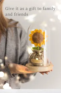 Handgehäkelte Sonnenblume in Glaskuppel mit LED-Lichtern und rustikaler Jutasis