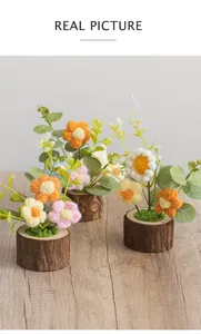 Detail of three handmade crochet flowers in wooden pots with eucalyptus leaves