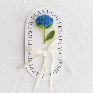 Detail of hand-crocheted blue rose with green leaf and Love Is Eternal ribbon